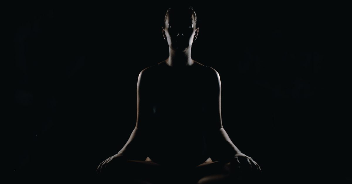 woman sitting meditating in darkness